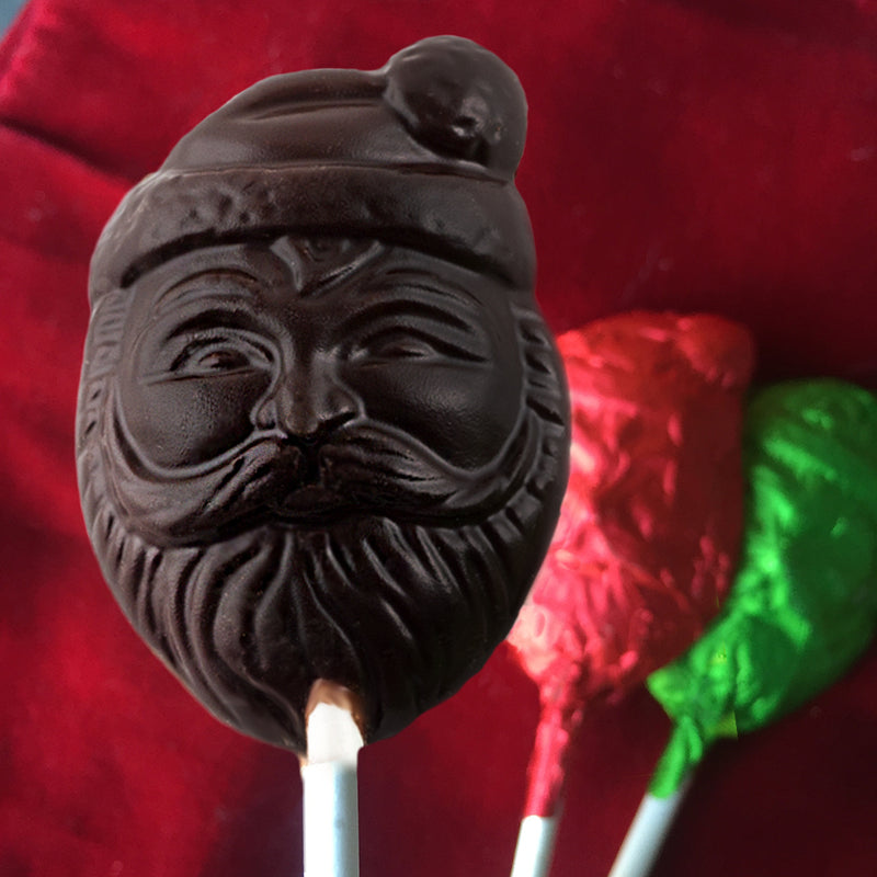 One dark chocolate lollipop with two lollipops with red and green foil on a red background
