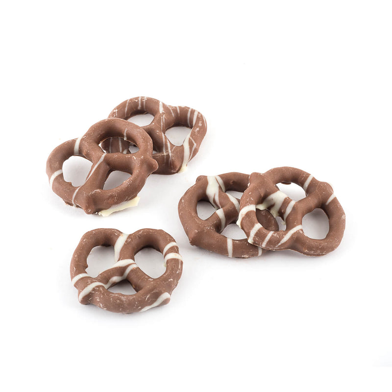 Close up milk chocolate coated pretzels that are dressed with lines of white chocolate