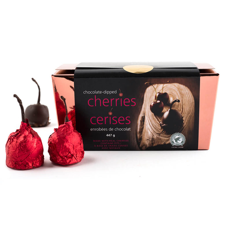 Copper box of chocolate dipped marinated cherries with two red foiled cherries next to the box.