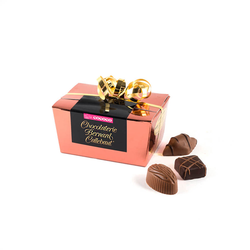 Chocolaterie Bernard Callebaut® copper chocolate box with gold ribbon and three chocolates next to box